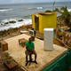 Roberto Figueroa Caballero sitting on a small table in his home that was destroyed by Hurricane Maria on the coast of San Juan, Puerto Rico. Photo: AP